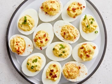 Overhead view of deviled eggs on a platter with different toppings.