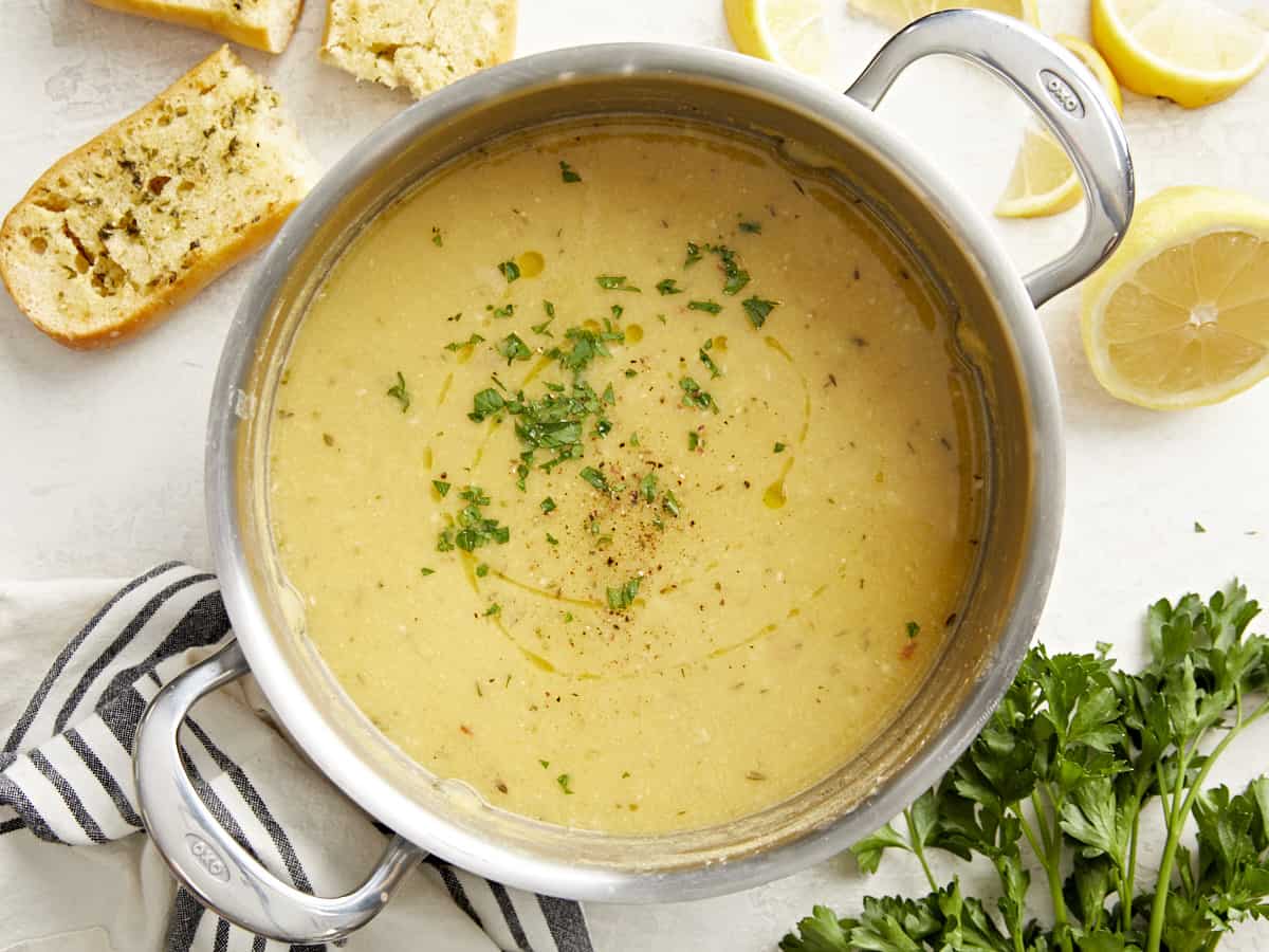 Overhead view of a pot full of lemony chickpea soup with garlic bread on the side.