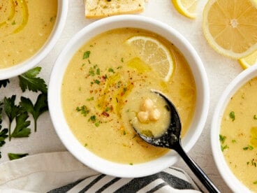 Overhead view of a bowl of lemony chickpea soup with a spoon in the middle.
