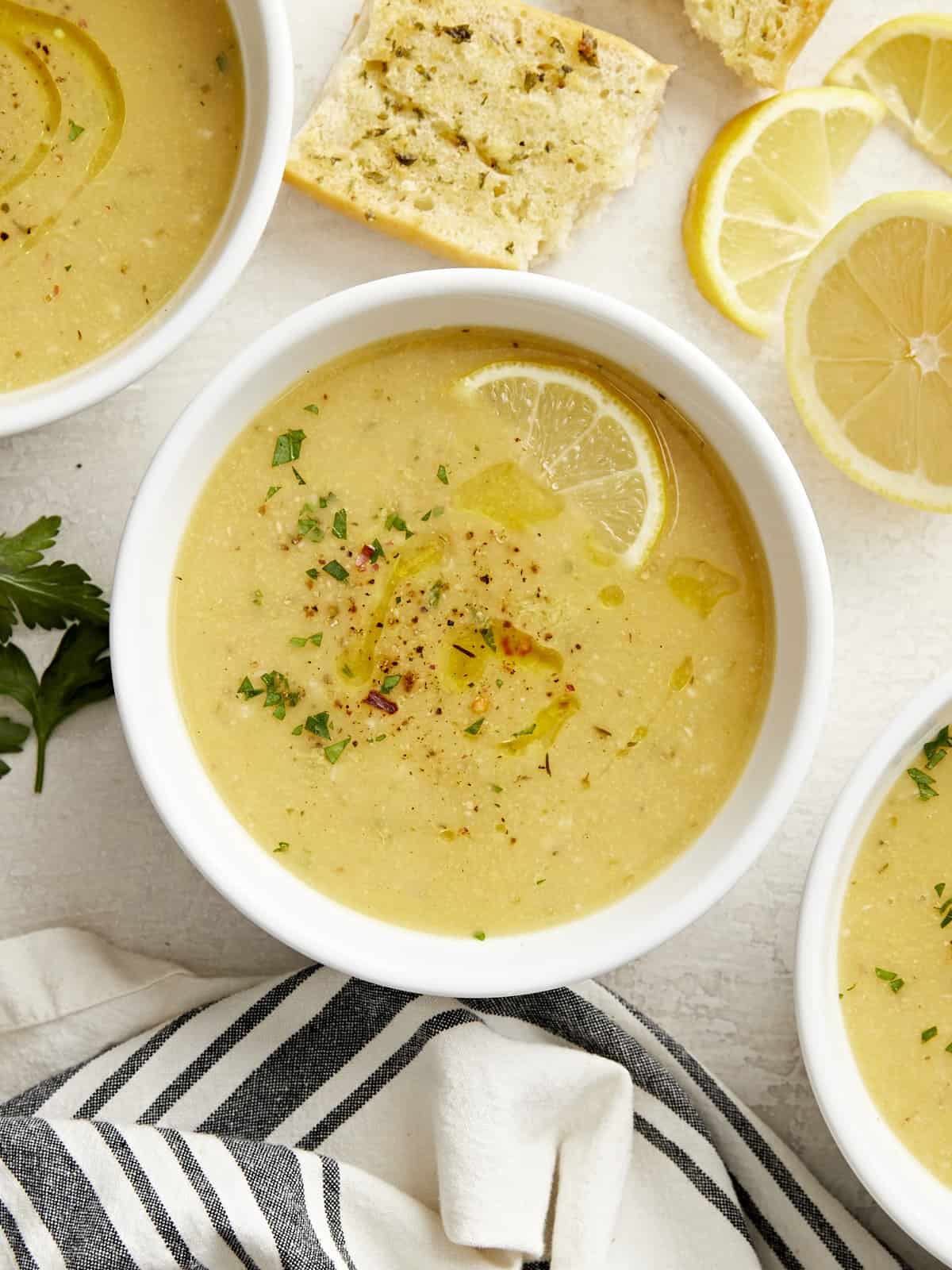 Overhead view of three bowls of lemony chickpea soup garnished with a lemon slice.
