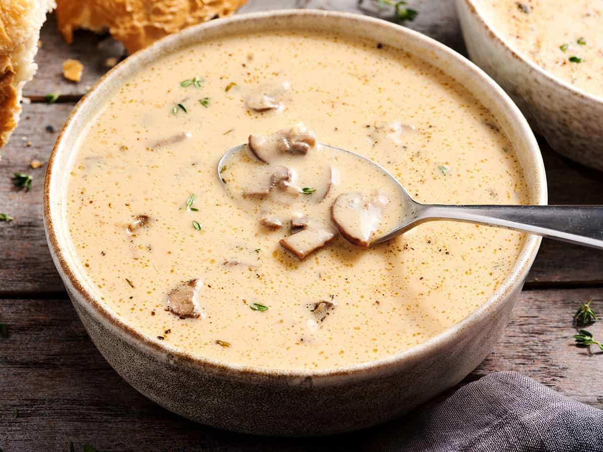 Side view of creamy mushroom soup in a bowl with a spoon.