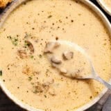 Overhead view of creamy mushroom soup in a bowl with a spoon.