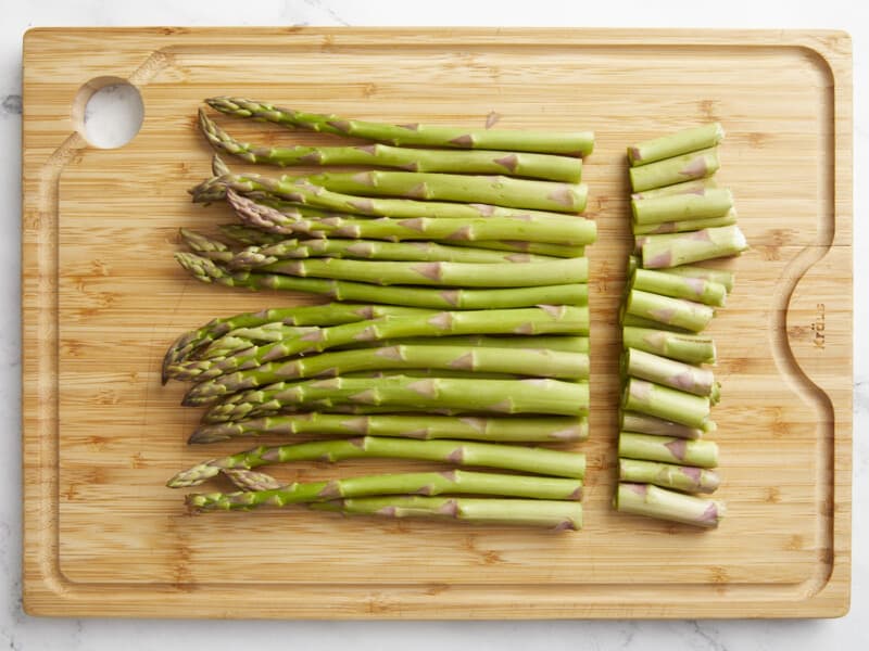 a bunch of asparagus with the ends cut off on a cutting board.