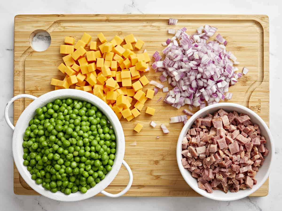 ingredients for pea salad on a cutting board.