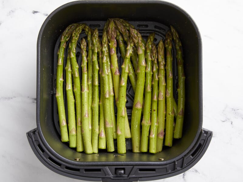raw seasoned asparagus in an air fryer.
