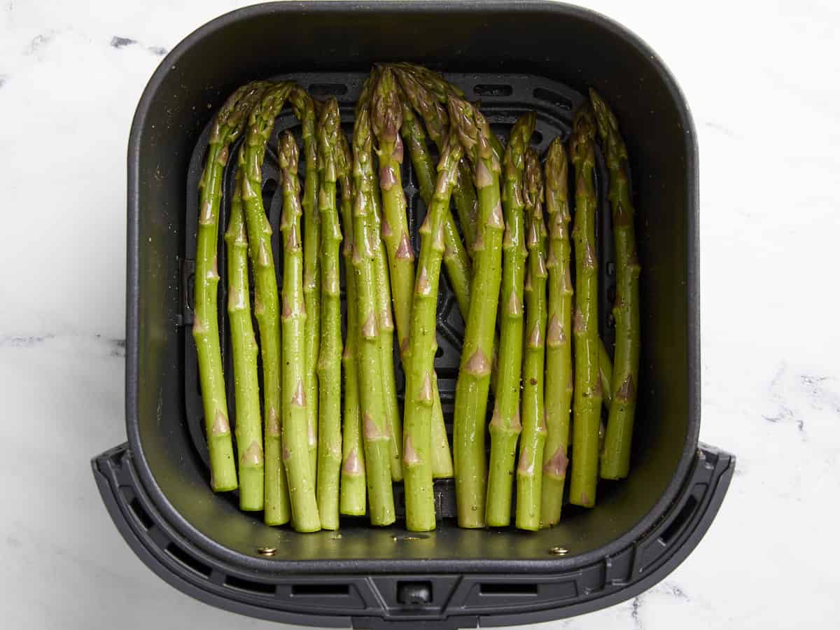 raw seasoned asparagus in an air fryer.