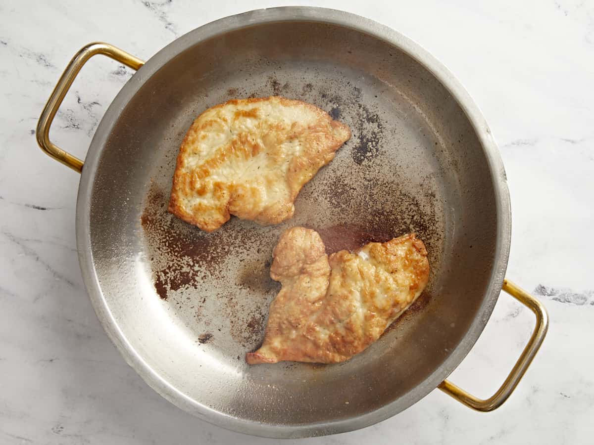 2 chicken breasts cooking in a pan.
