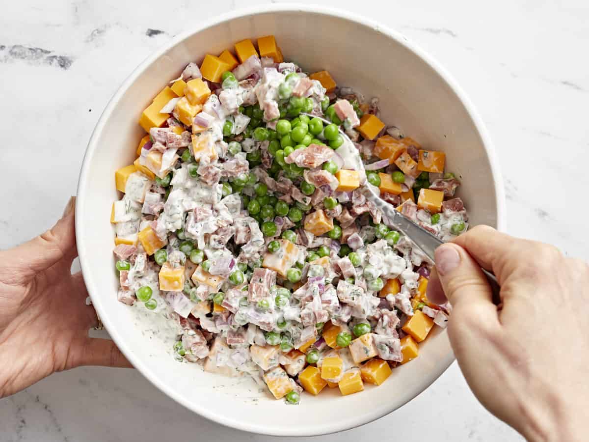 ingredients for pea salad in a white bowl.