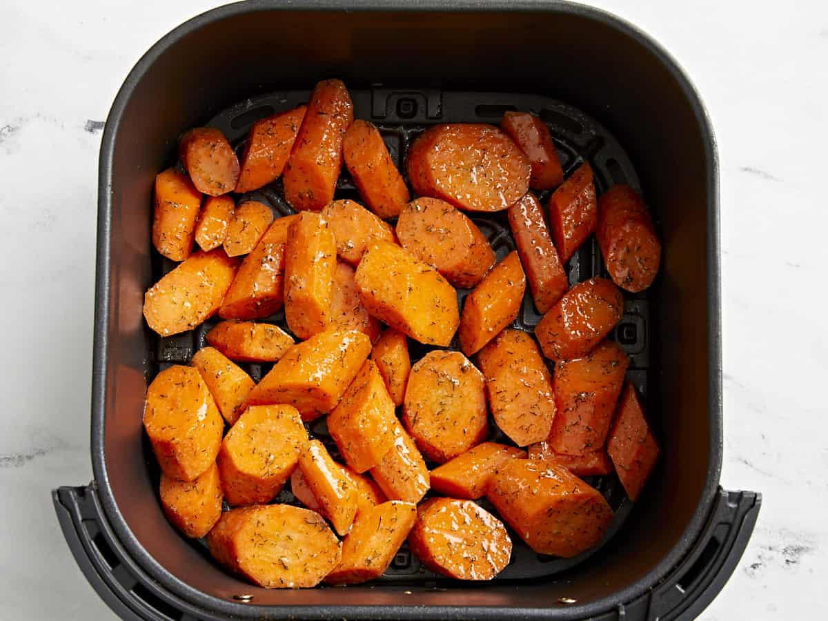Uncooked carrots added to the air fryer basket.