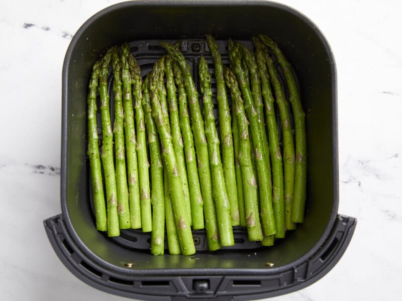 cooked seasoned asparagus in an air fryer.