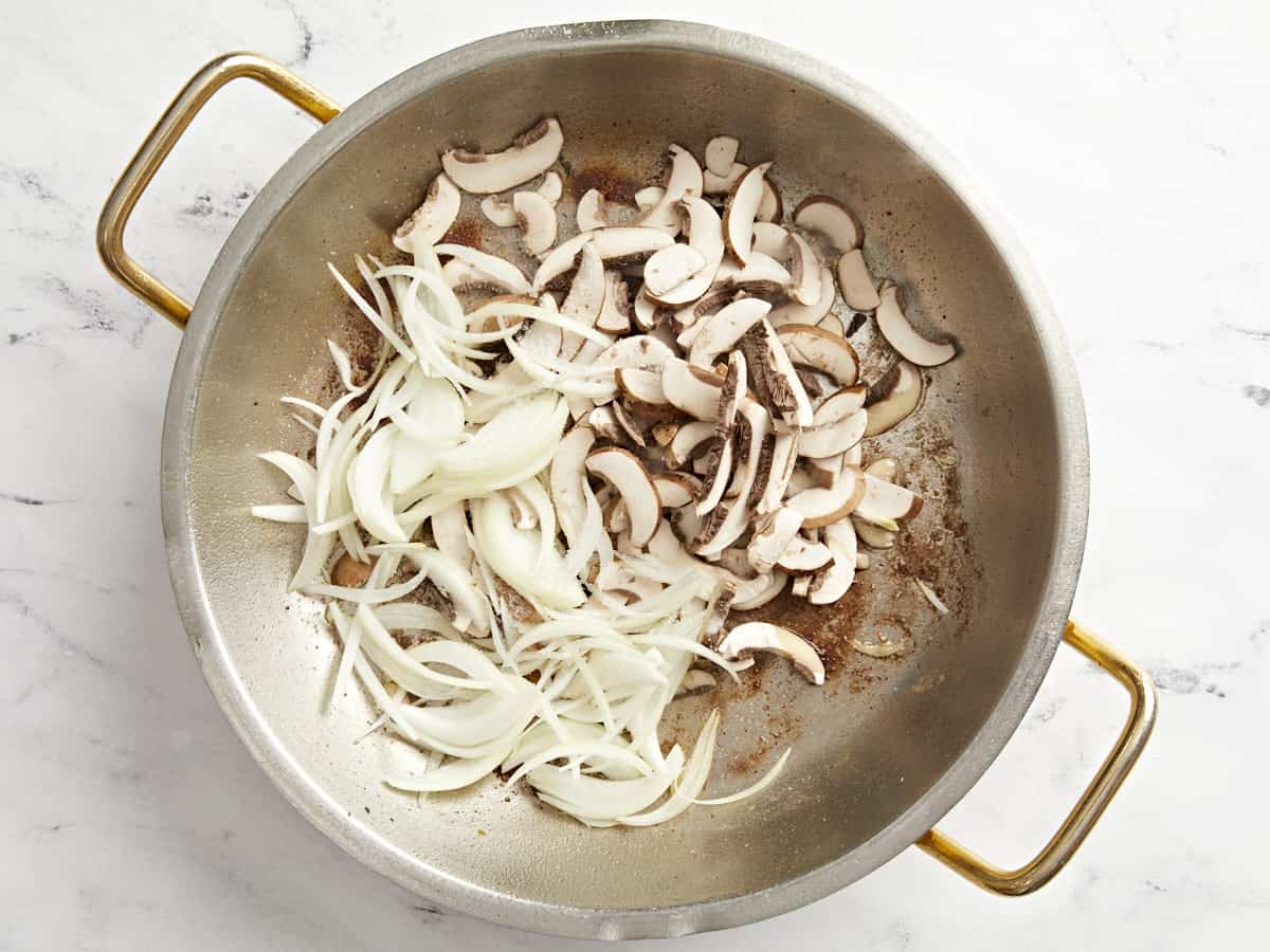 sliced onions and mushrooms in a pan.