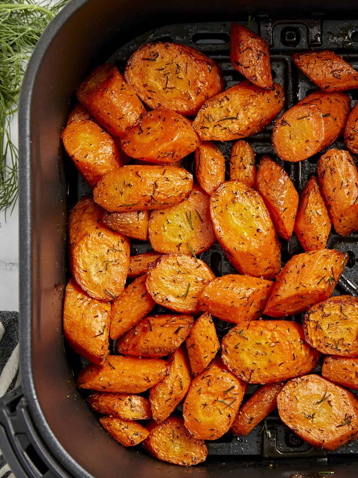 Top view of cooked carrots in a black air fryer basket.