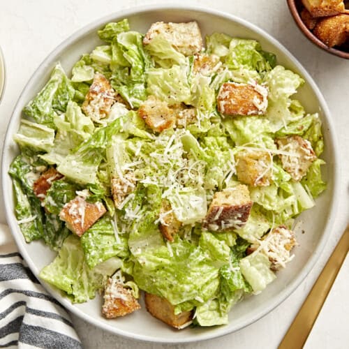 Overhead view of a plate of caesar salad with a gold fork on the side.