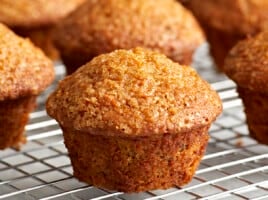 Close up side view of carrot cake muffins on a cooling rack.