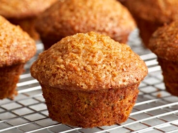 Close up side view of carrot cake muffins on a cooling rack.