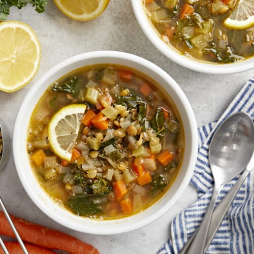 Top view of 2 bowls of Mediterranean lentil soup with lemon slices.