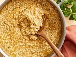 overhead view of a wooden spoon in a pan of parmesan risotto.