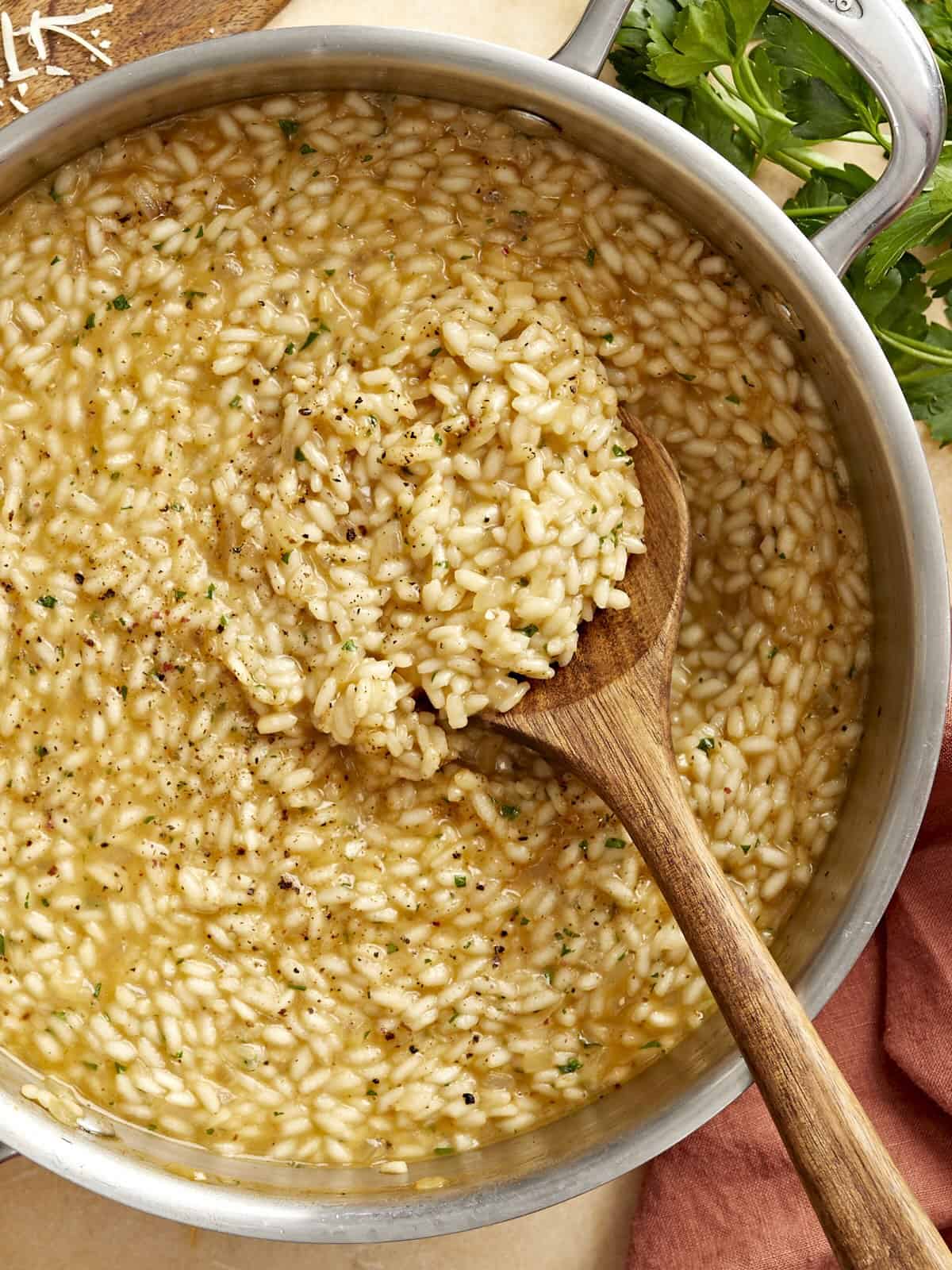 overhead view of a wooden spoon in a pan of parmesan risotto.