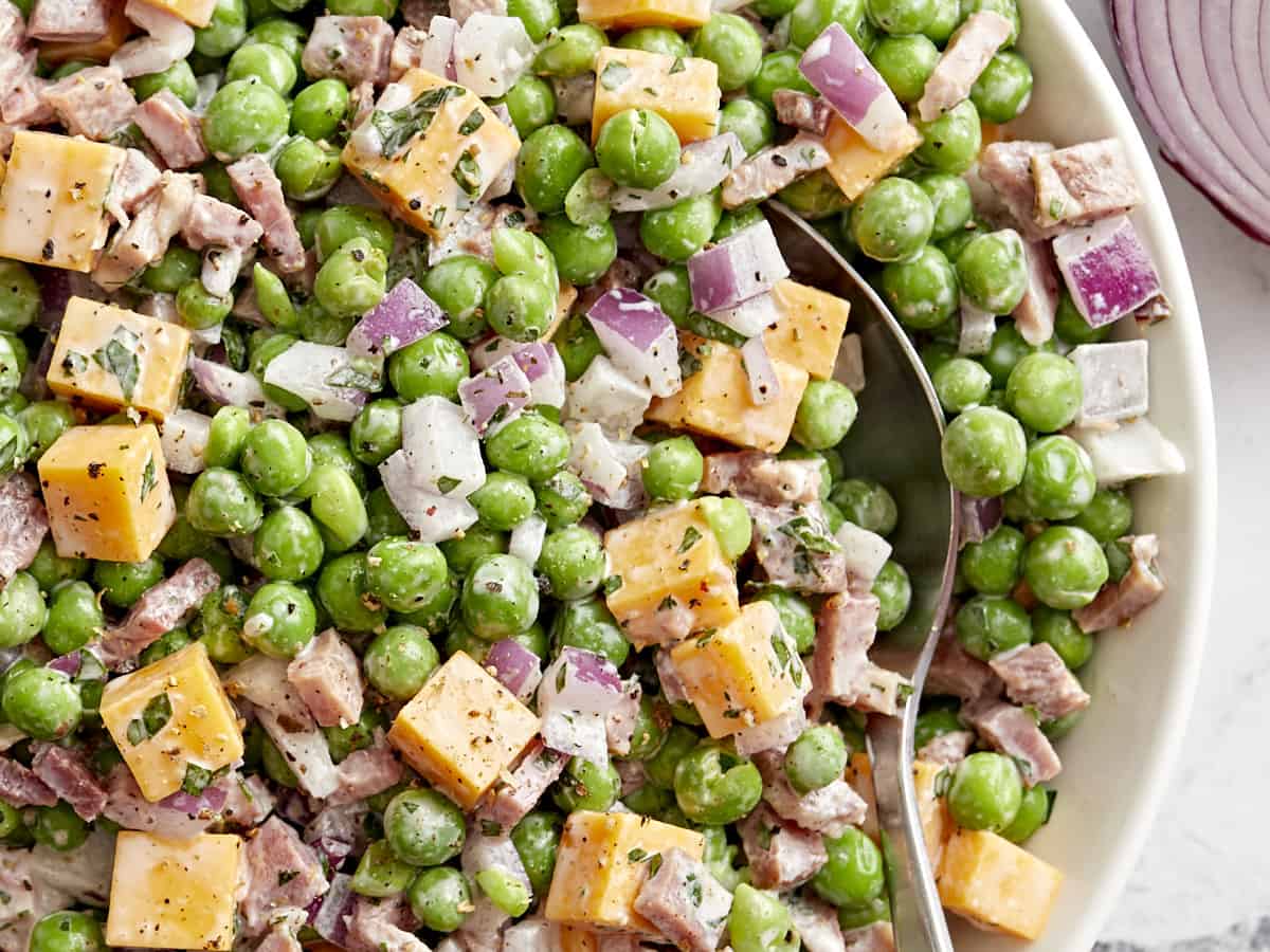 close up view of pea salad with a spoon.