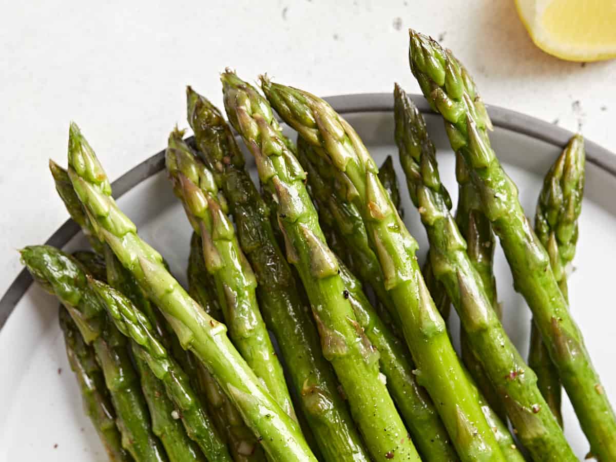 close up of sauteed asparagus tips on a plate.