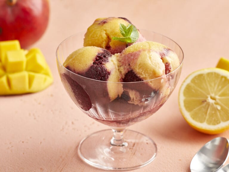 a serving of swirled yellow and purple sorbet in a glass coupe.