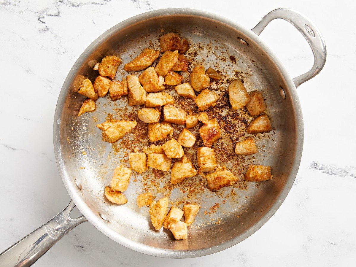 Browned chicken pieces in a skillet. 