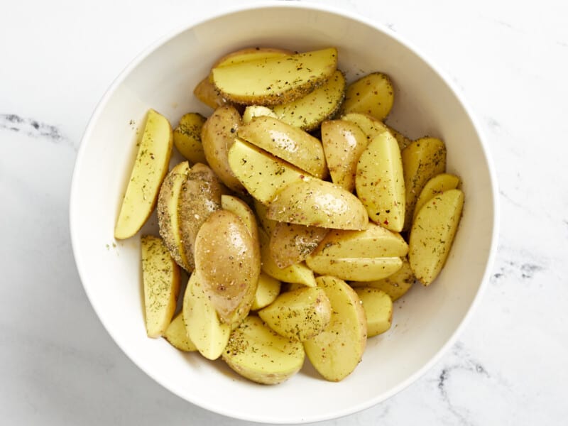 seasoned halved baby potatoes in a white bowl.