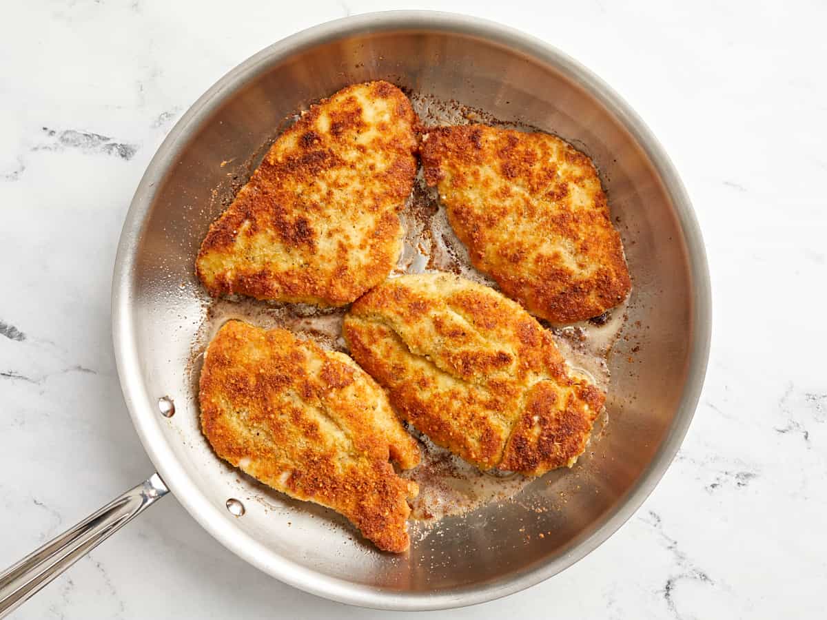 4 fried chicken breasts in a stainless skillet.