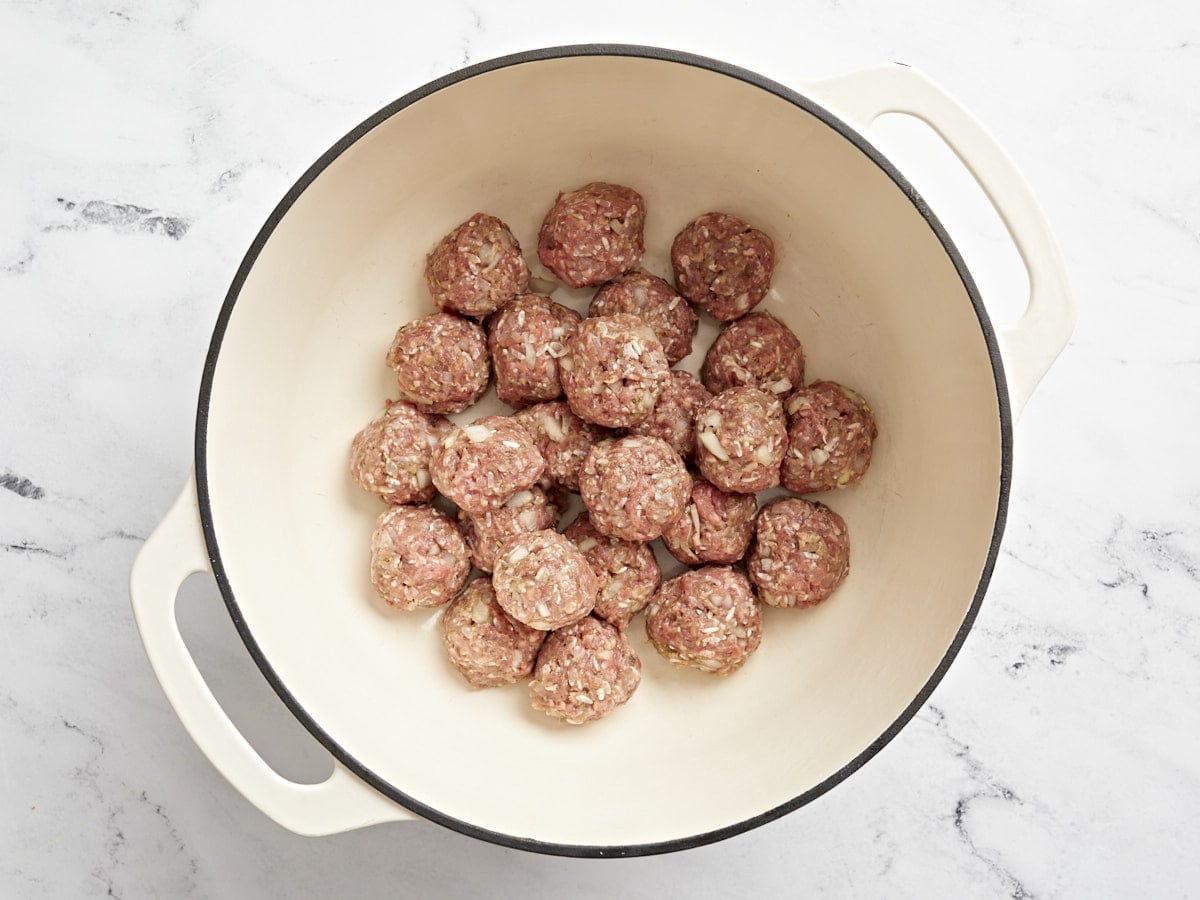 Porcupine meatballs added to a dutch oven.