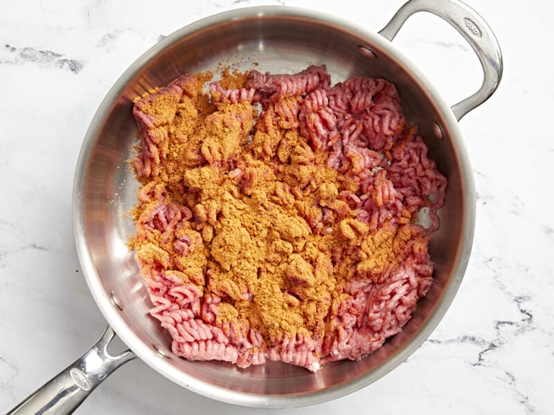 raw ground beef and spices in a frying pan.