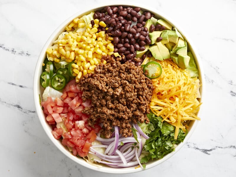 overhead view of taco salad with ingredients separated in a white bowl.