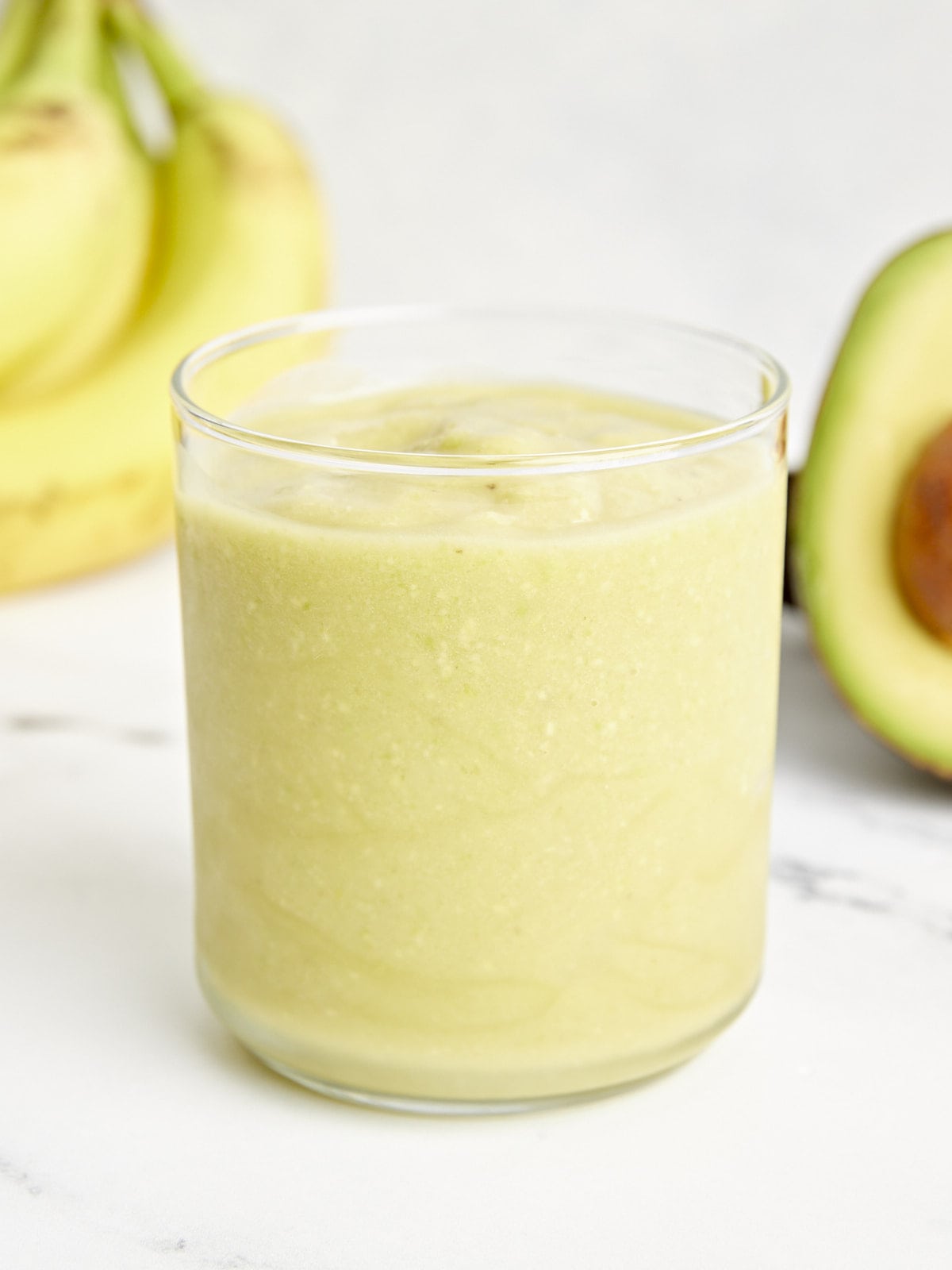 close up of an avocado smoothie in a green glass.