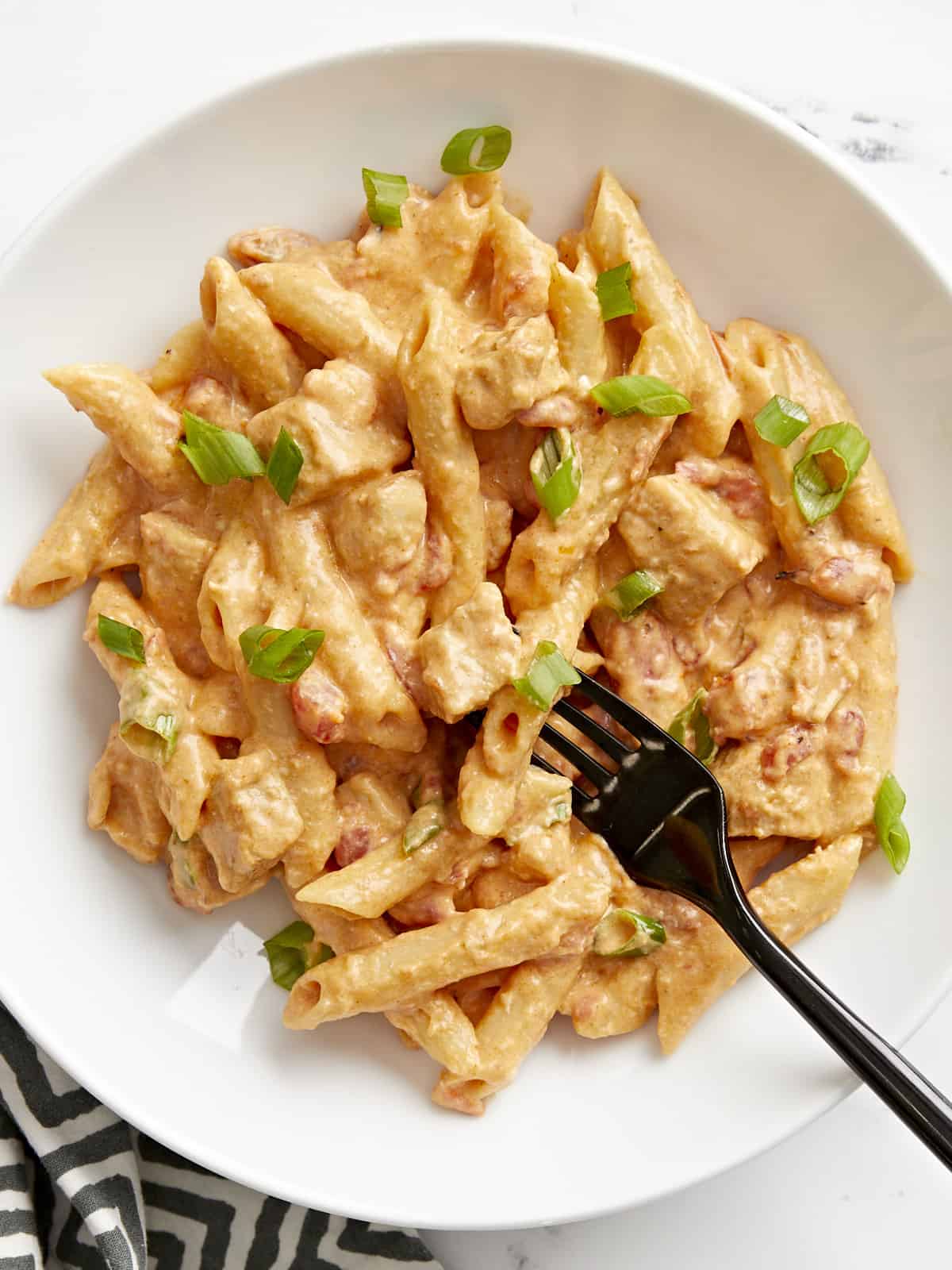 Close-up top view of a bowl full of buffalo chicken noodles with a fork.