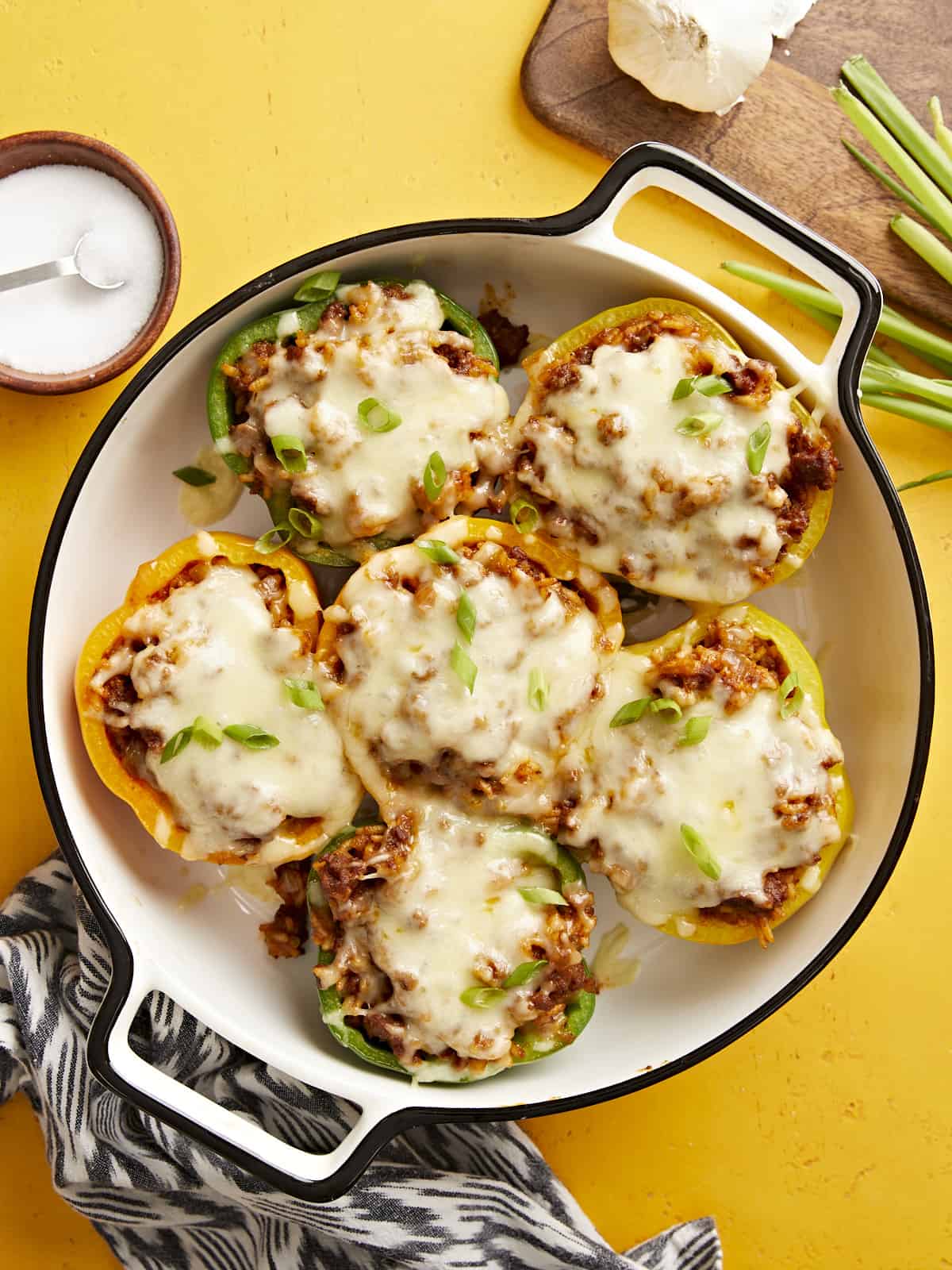 Overhead view of chorizo stuffed bell peppers in a baking dish on a yellow background.