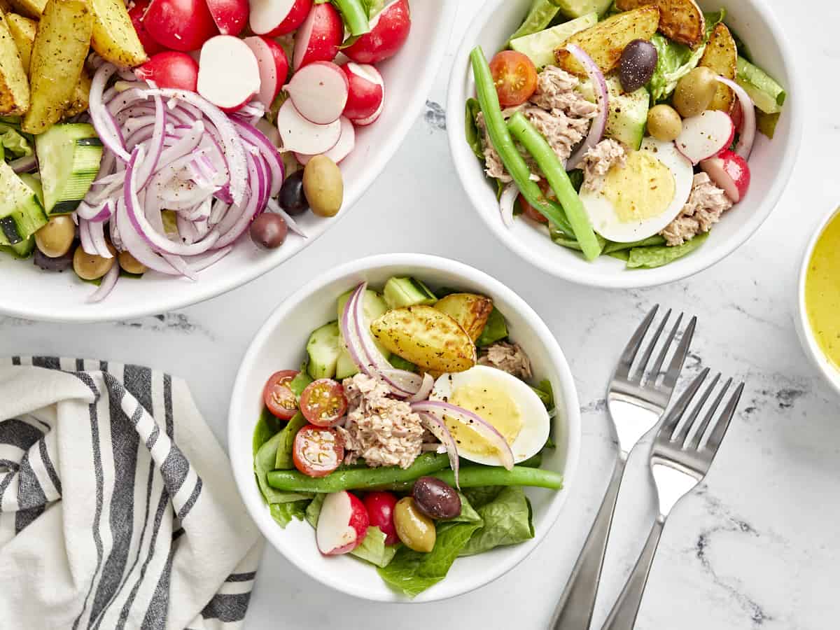 servings of nicoise salad in white bowls.