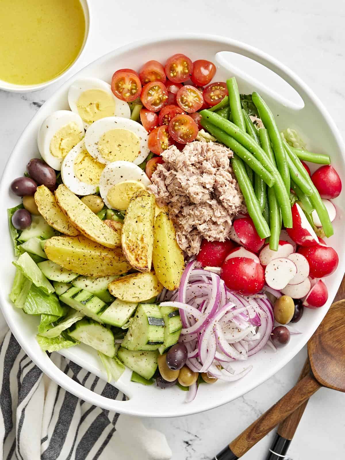close-up overhead view of nicoise salad in a white bowl.