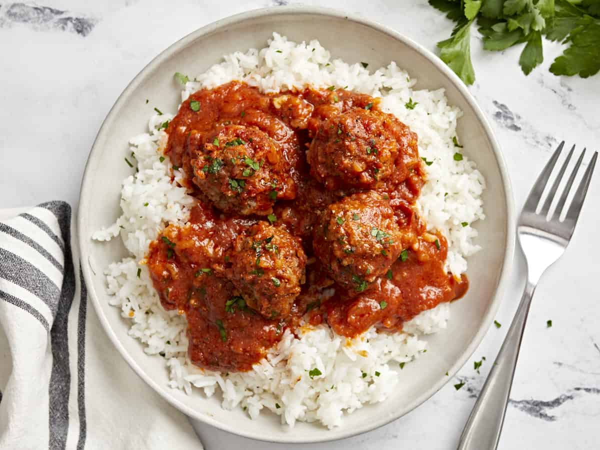 Top view of porcupine meatballs on a serving plate with white rice.