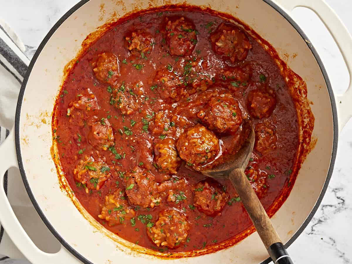 Top view of porcupine meatballs in a Dutch oven covered in tomato sauce.