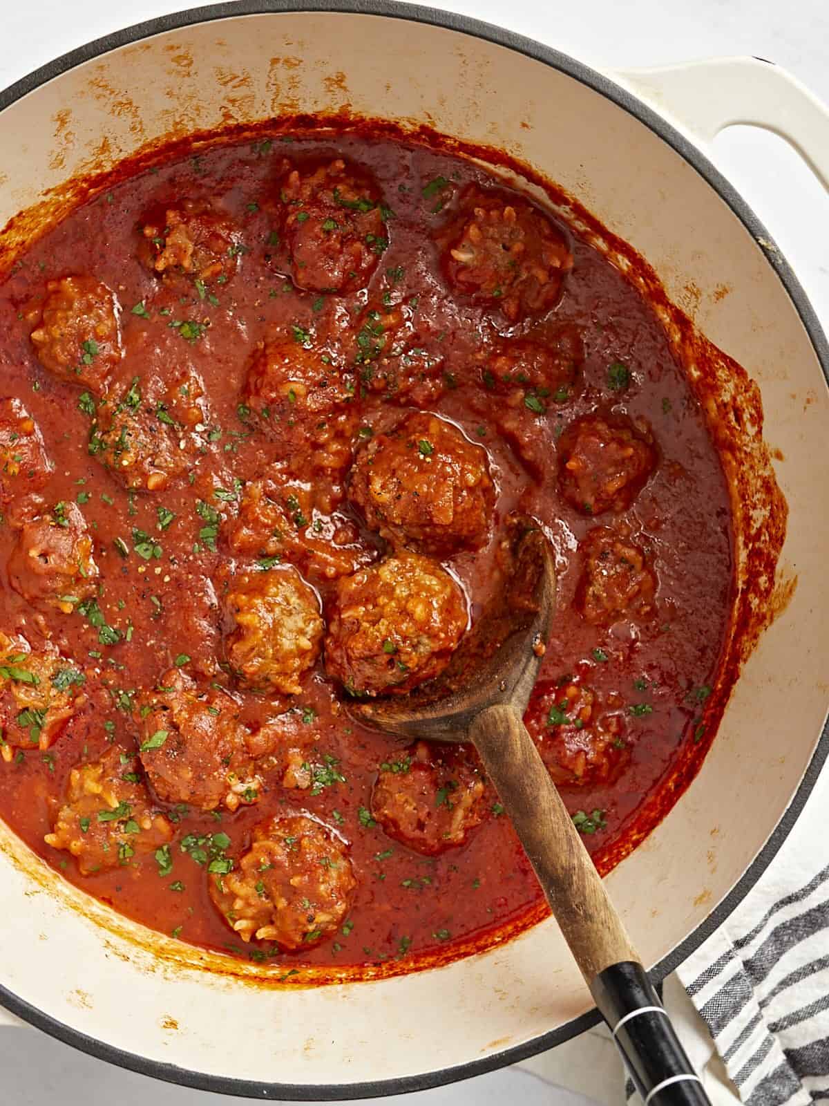 Overhead view of porcupine meatballs in a dutch oven covered in tomato sauce.
