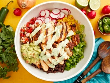 creamy avocado dressing drizzled over santa fe salad in a large white bowl.