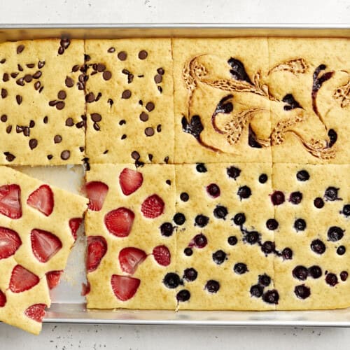 Top view of sheet pan pancakes cut into squares with one slice lifted out.