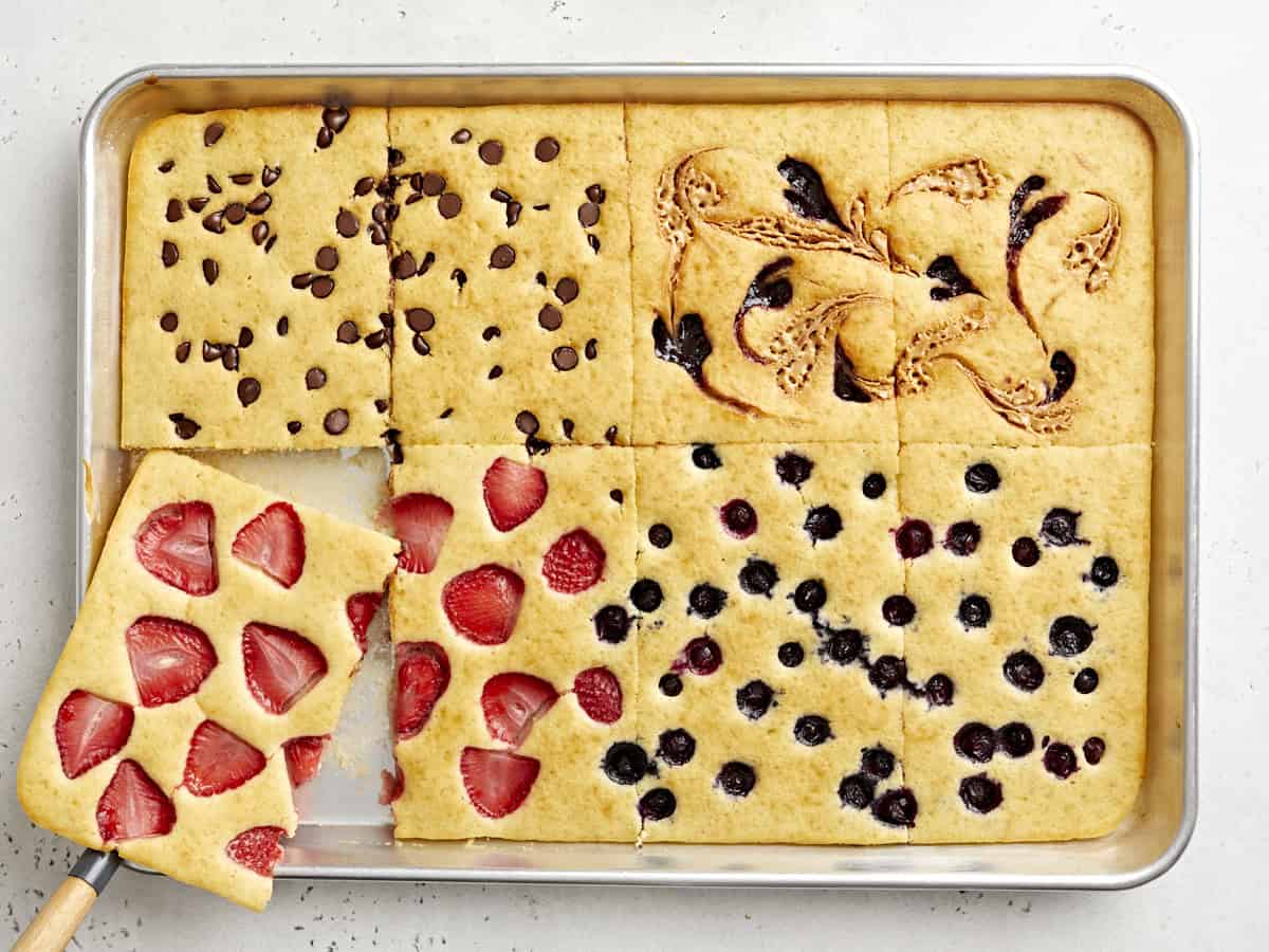 Overhead view of sheet pan pancakes cut into squares with one slice being lifted out.