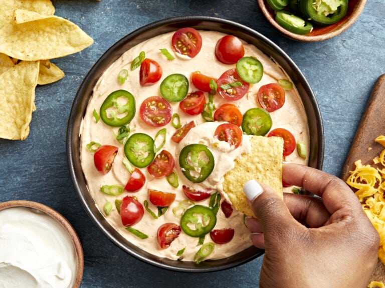 Overhead view of Taco Dip in a serving bowl with a chip scooping some out.