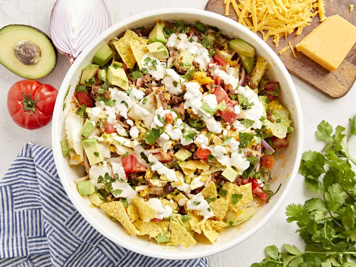 Top view of taco salad with creamy white dressing in a white bowl.