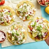 holding a tostada over a table topped with tostadas.