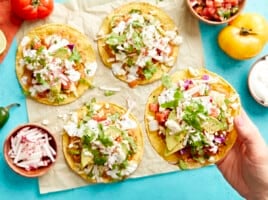 holding a tostada over a table topped with tostadas.