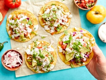 holding a tostada over a table topped with tostadas.