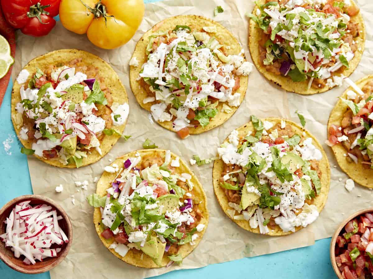 overhead view of tostadas on a piece of parchment paper on a blue table.