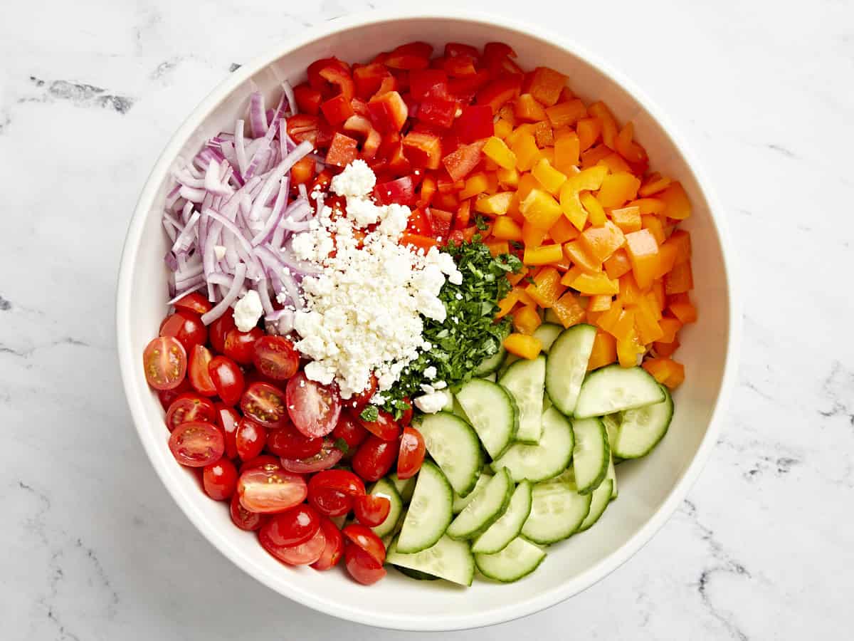 Pasta salad ingredients added to a large white serving bowl.