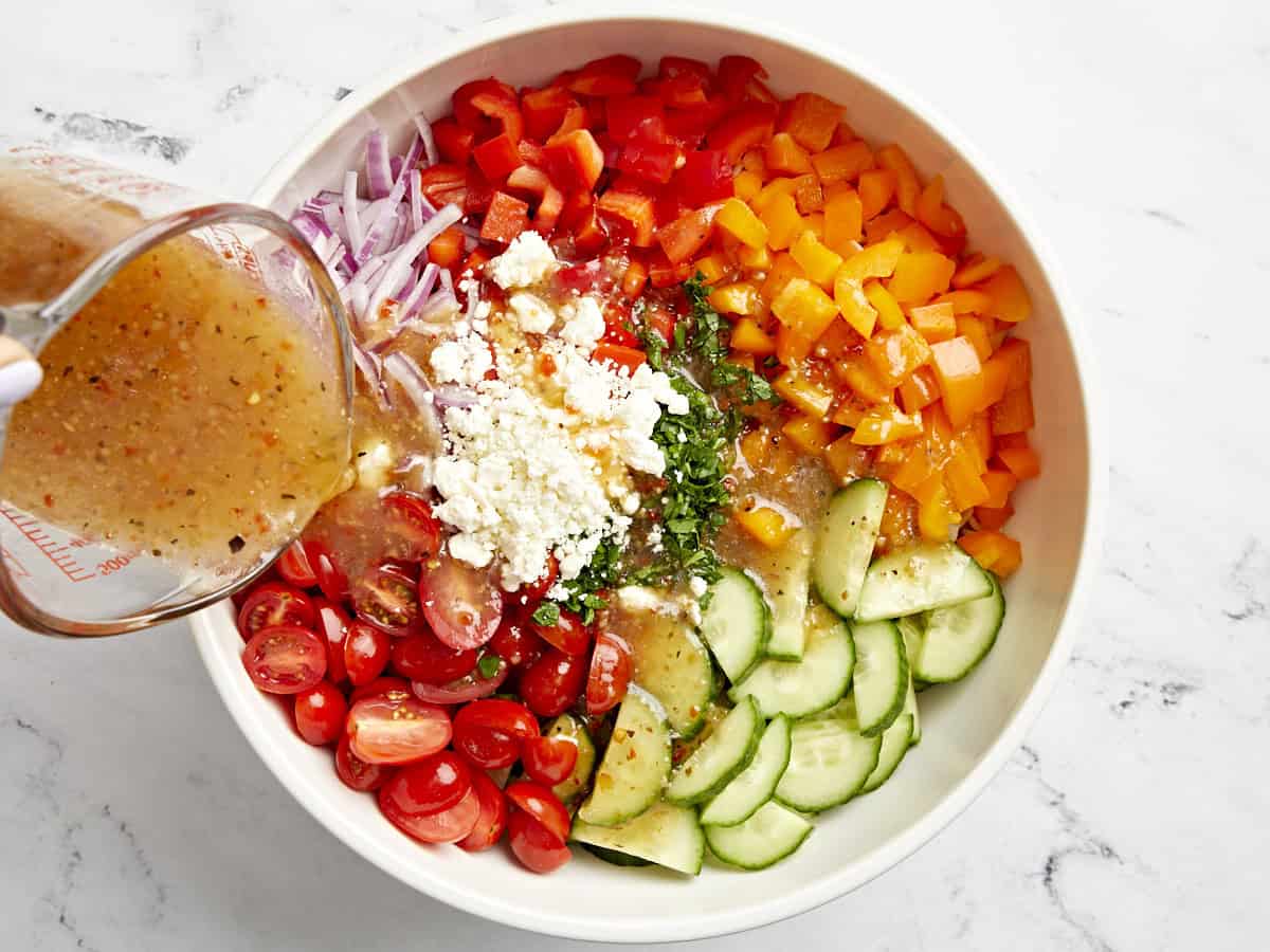 Italian dressing being poured over pasta salad.